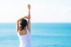 海辺で背伸びする女性