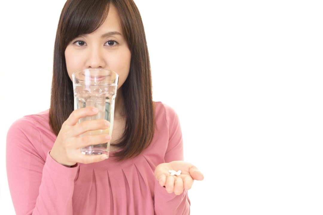 水を飲みながらカプセルを差し出す女性